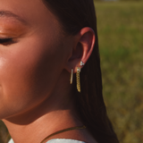 Side of Burdlife Model's head displaying 3 earrings including the Luxe Oval Hoops, the Refined Single Chain Earring and the Modish Triple Crystal Studs. 